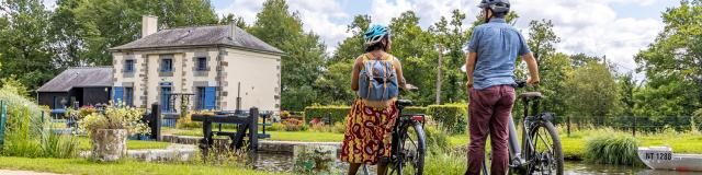 A vélo devant une maison éclusière du canal d'Ille-et-Rance