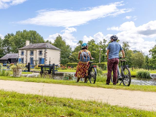 A vélo devant une maison éclusière du canal d'Ille-et-Rance